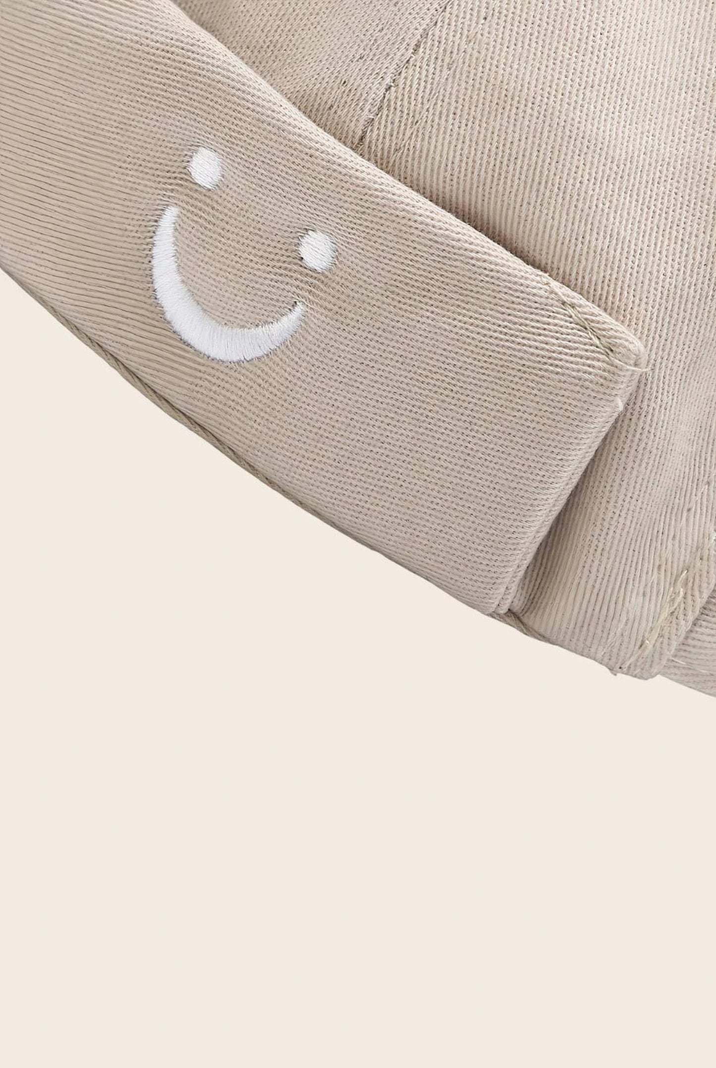 Gros plan sur le patch smiley brodé du bonnet docker beige