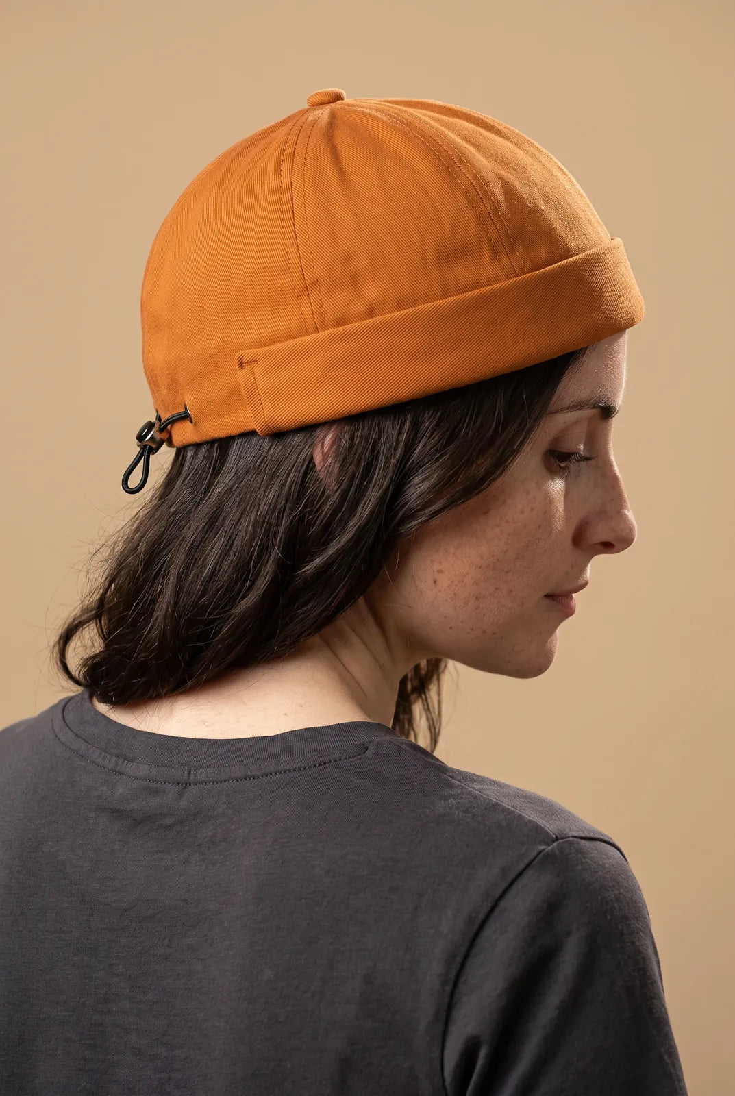Bonnet docker And orange porté par une femme, vue de dos sur la fermeture