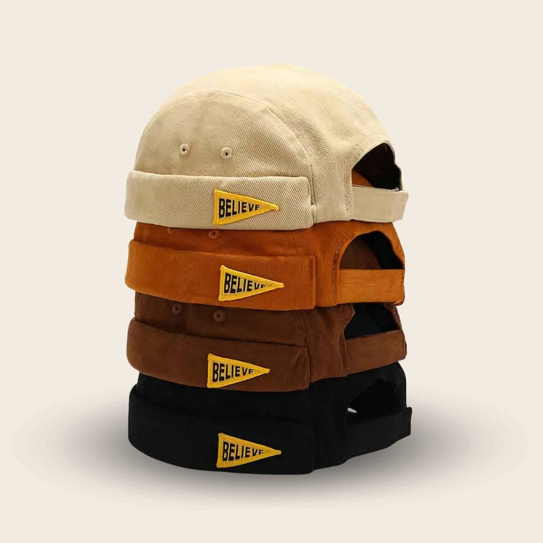 Les 4 coloris du bonnet docker Believe empilés : beige, orange, marron et noir
