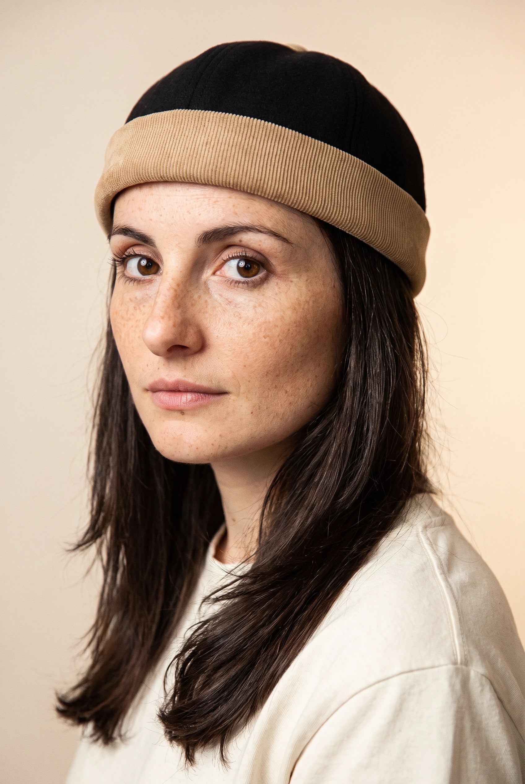 Bonnet docker Bicolore noir et camel porté par une femme, portrait