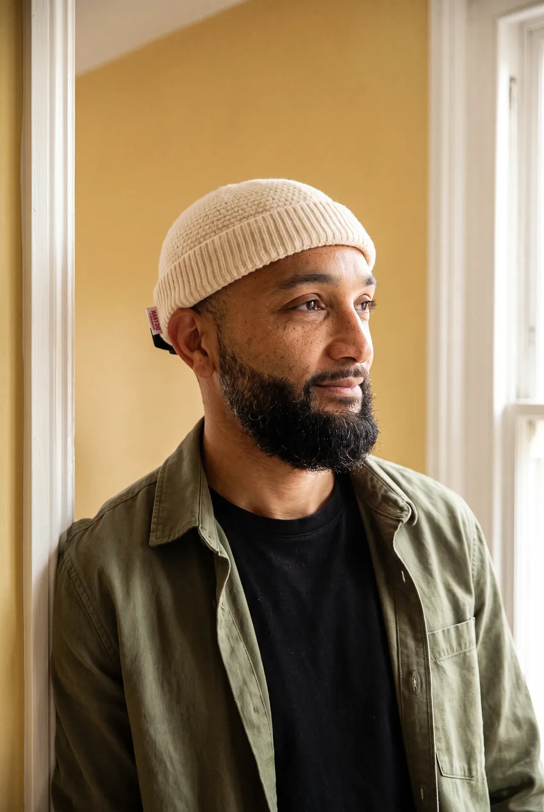 Bonnet docker Grosse Maille beige porté par un homme en intérieur