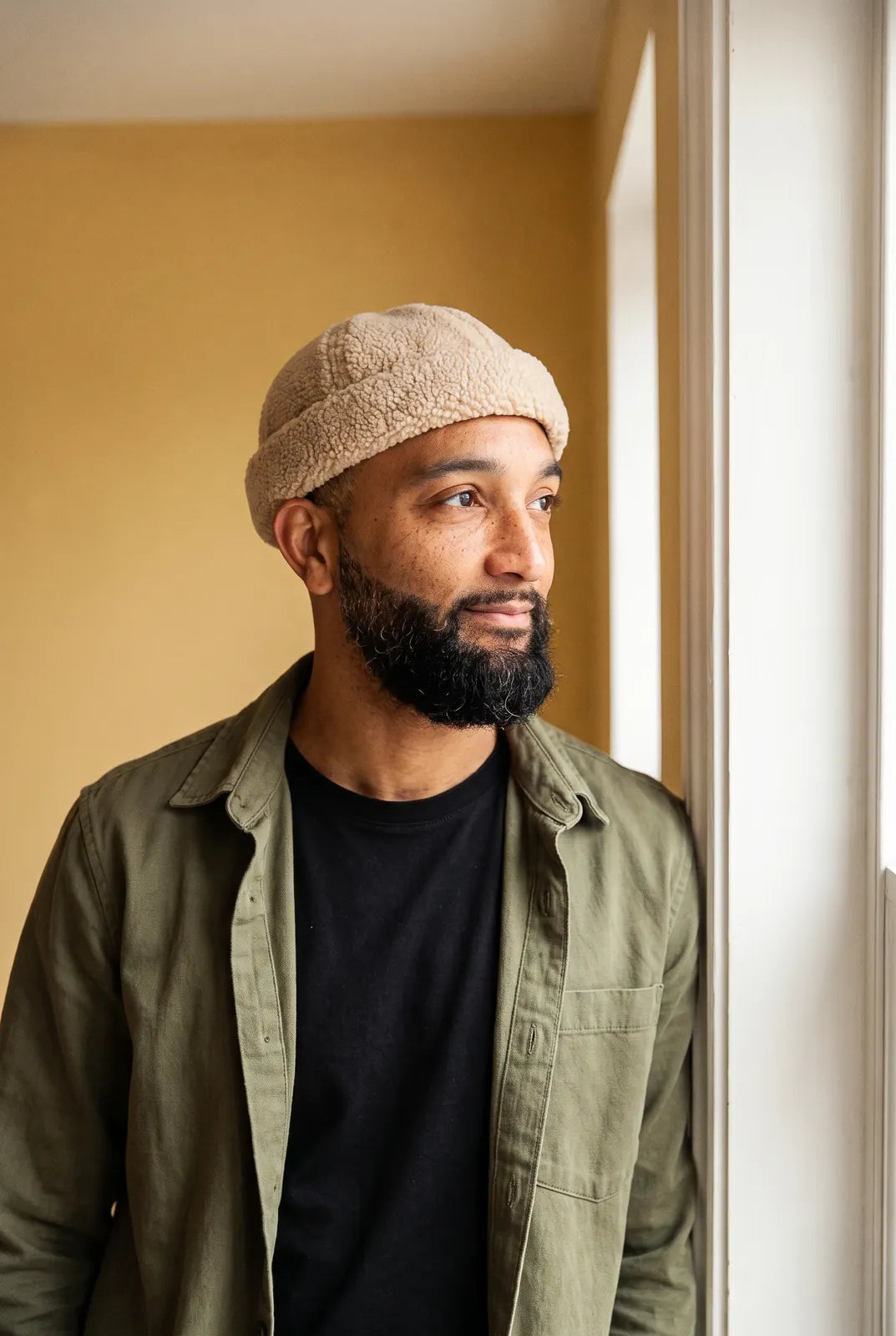 Bonnet docker Mouton retourné beige porté par un homme en intérieur