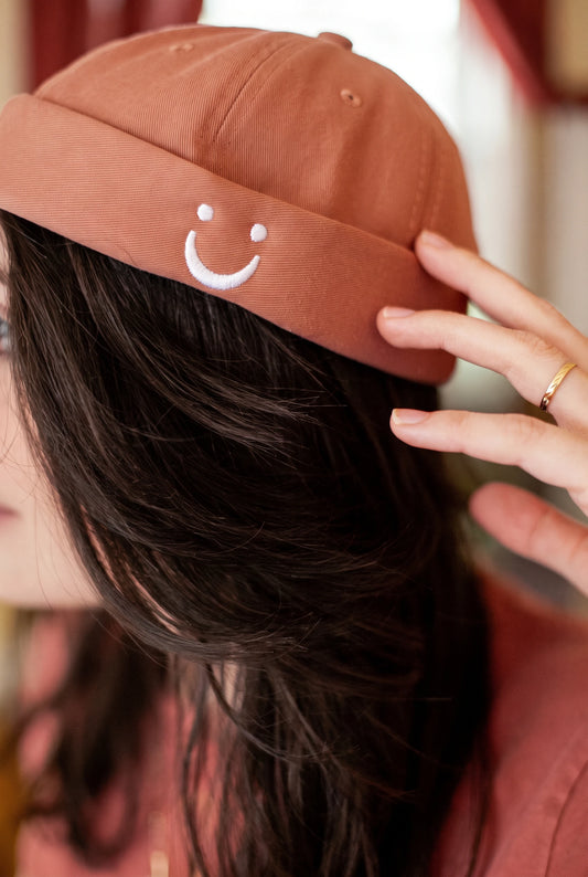 Bonnet docker Smiley terracotta, gros plan sur le patch porté par une femme