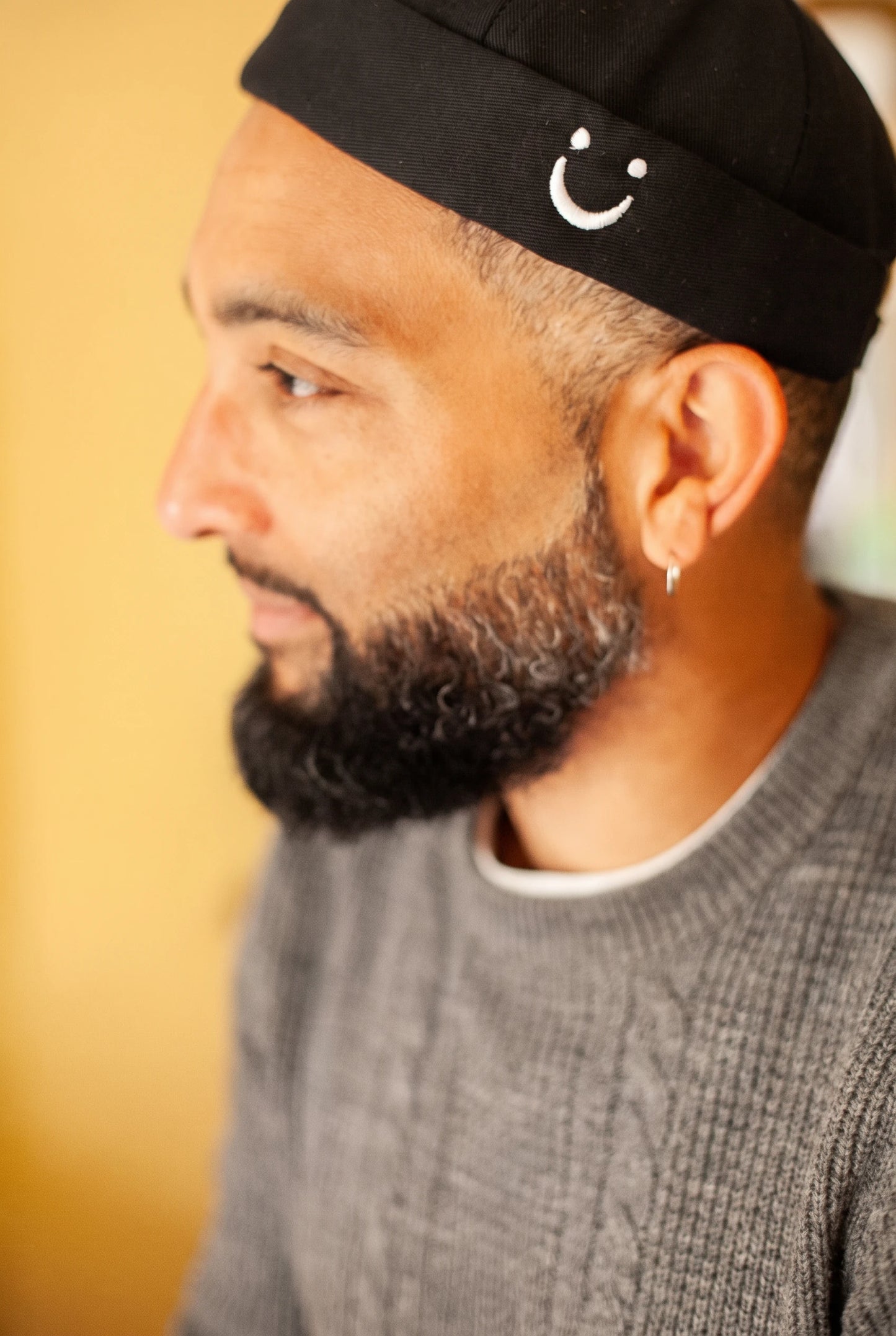 Bonnet docker Smiley noir porté par un homme, gros plan sur le patch